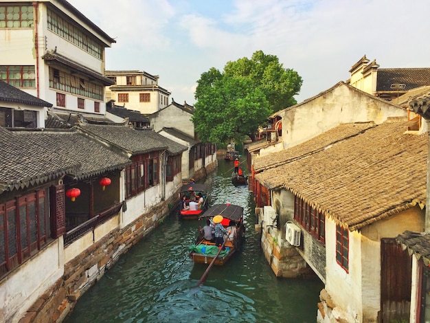 Photo high angle view of people on boats sailing at canal amidst houses