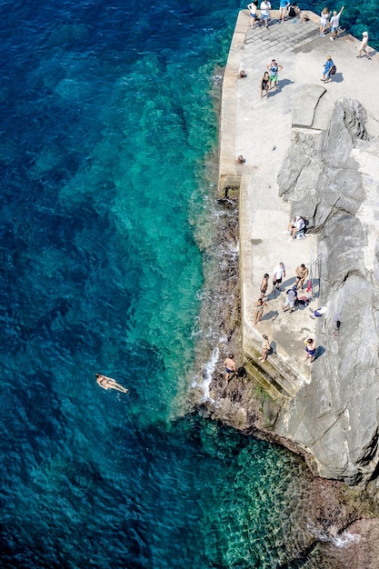Foto vista ad alto angolo delle persone sulla roccia vicino al mare