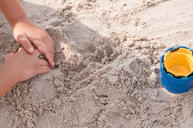 Высокоугольный вид руки человека, играющего с песком на пляже