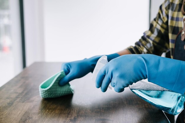 Photo high angle view of person using disinfectant to clean table at home