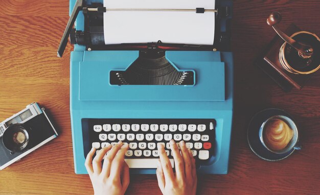 Photo high angle view of person using typewriter with camera and coffee cup on table