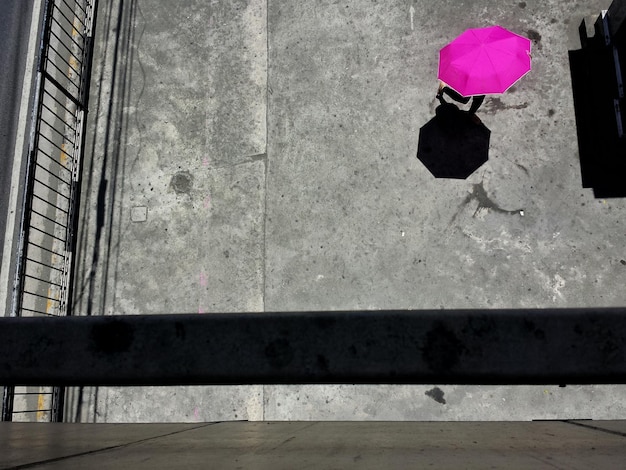 Photo high angle view of person walking with pink umbrella at street on sunny day