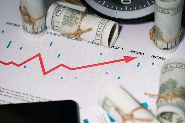 High angle view of phone with paper currency and chart on table