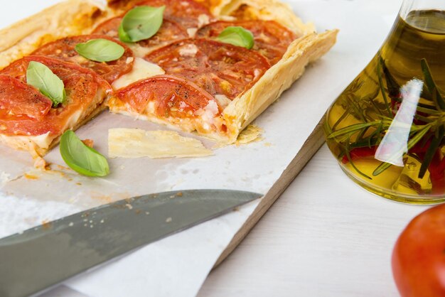 Foto vista ad alto angolo della pizza con coltello da cucina e olio sul tavolo