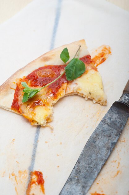 Foto vista ad alto angolo di una pizza con un coltello su carta cera