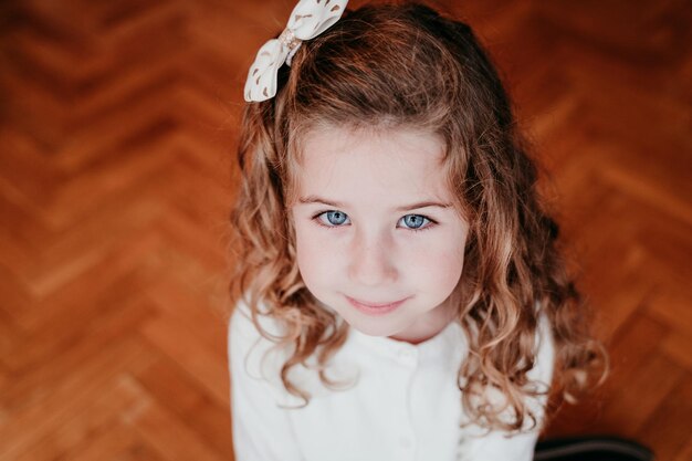 High angle view portrait of cute girl sitting on hardwood floor