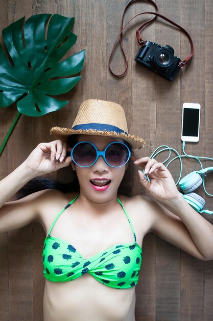 High angle view portrait of woman wearing sunglasses and hat while lying on hardwood floor