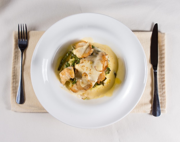 High Angle View of Prepared Saucy Dish Served in White Bowl at Place Setting with Fork and Knife