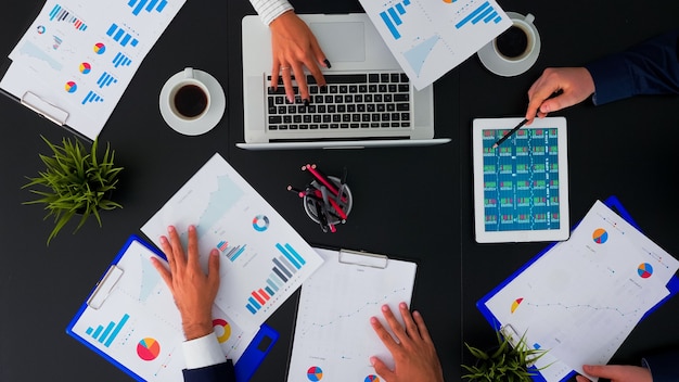 High angle view of professional business people meeting in conference room with company manager planning financial strategy using modern technology in corporate building