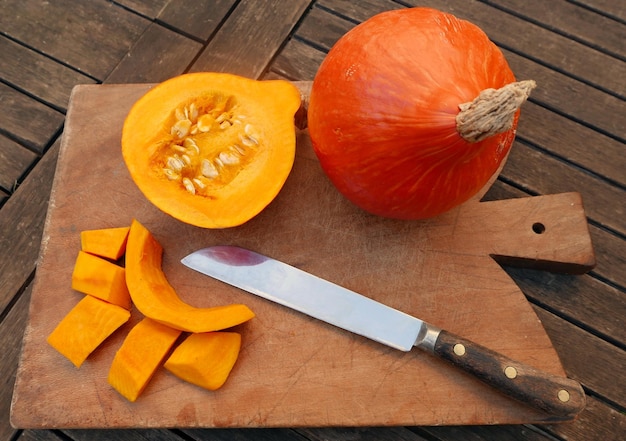 Foto vista ad alta angolazione di zucca e coltello su tavola da taglio a tavola di legno