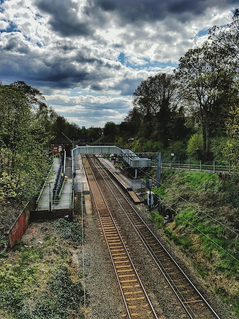 Photo high angle view of railroad track amidst trees against cloudy sky