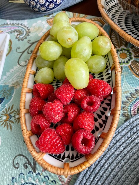 High angle view of raspberries and grapes in bowl on table