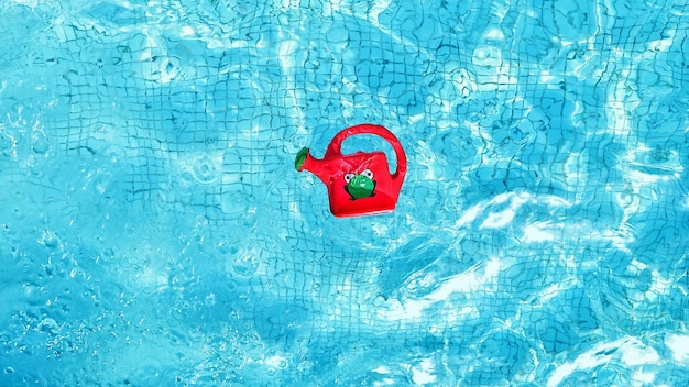 Foto vista ad alto angolo di una bottiglia rossa che galleggia nella piscina