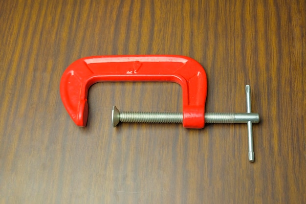 High angle view of red c-clamp on wooden table