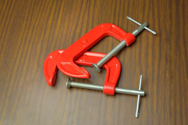 High angle view of red c-clamps on wooden table