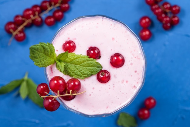 High angle view of a redcurrant cocktail with fruit garnish on blue background