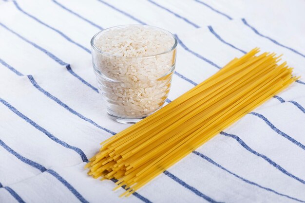 High angle view of rice in glass by pasta on table