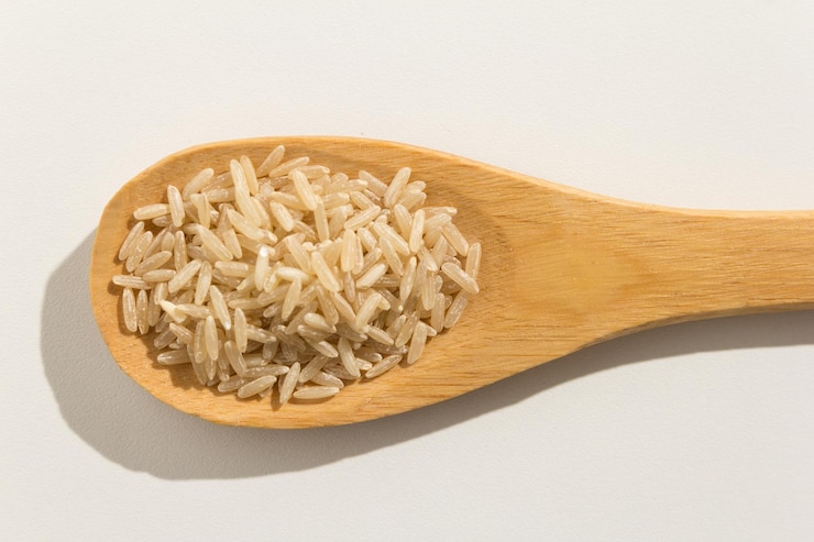 Photo high angle view of rice in wooden spoon over white background