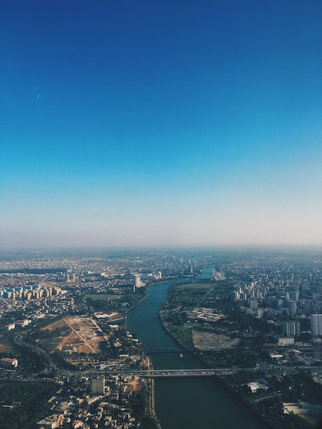 High angle view of river and buildings against clear blue sky