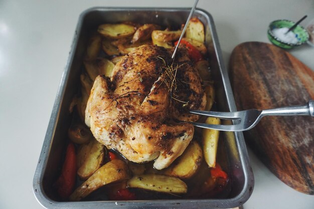 High angle view of roasted chicken and fried potatoes in container