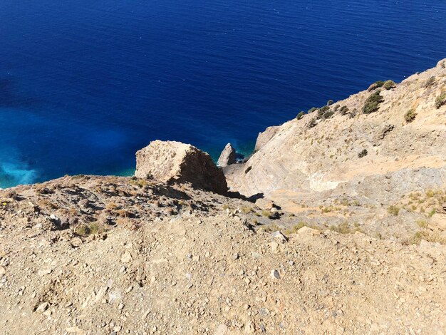 High angle view of rocks by sea against blue sky