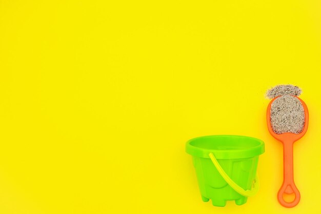 High angle view of sand pail and shovel on yellow background