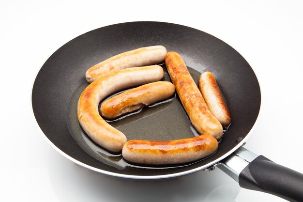 Photo high angle view of sausages in frying pan over white background