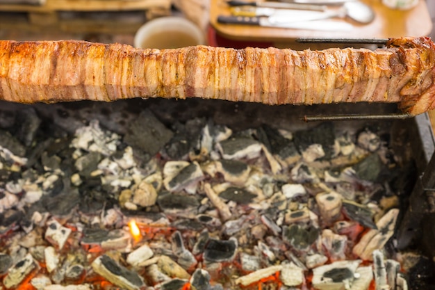 음식 카트 준비 스테이션에서 뜨거운 석탄 위에 침을 뱉어 굽는 Shawarma 고기의 높은 각도 보기