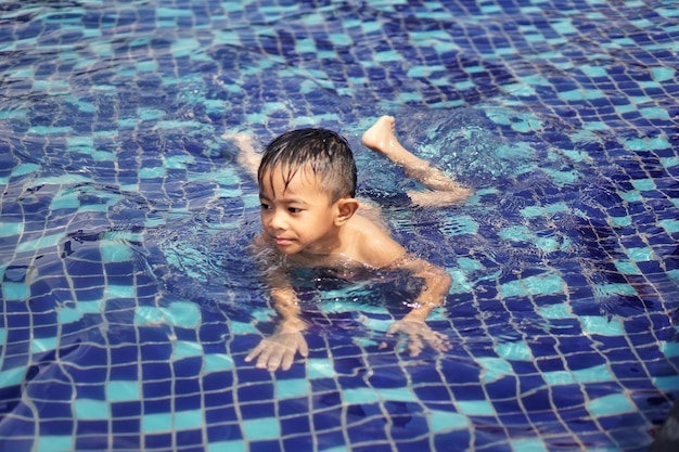 プールで泳いでいるシャツなしの男の子のハイアングルビュー