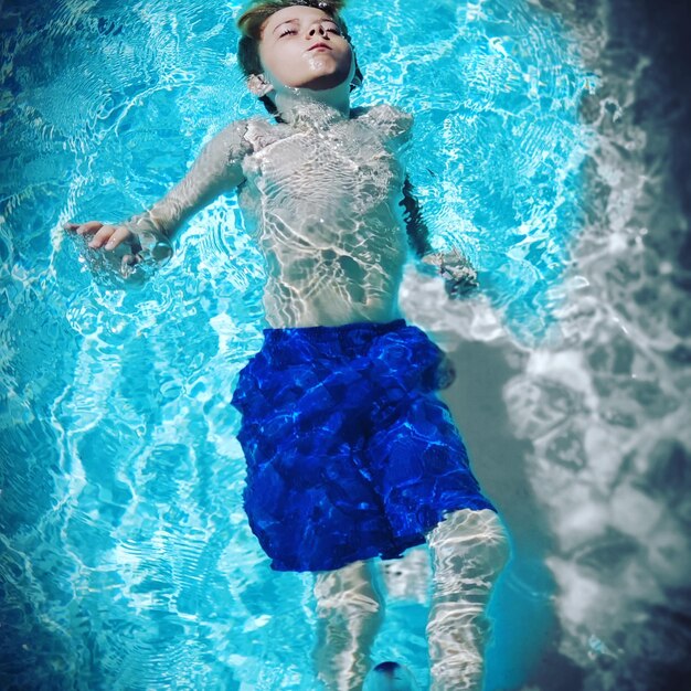 High angle view of shirtless boy swimming in pool