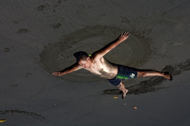 Foto vista ad alta angolazione di un uomo senza camicia che si rilassa sulla spiaggia