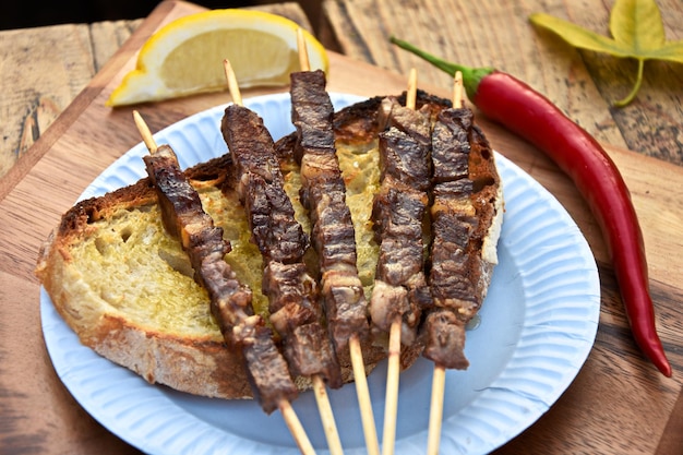 Photo high angle view of skewer meat and bread in plate on table