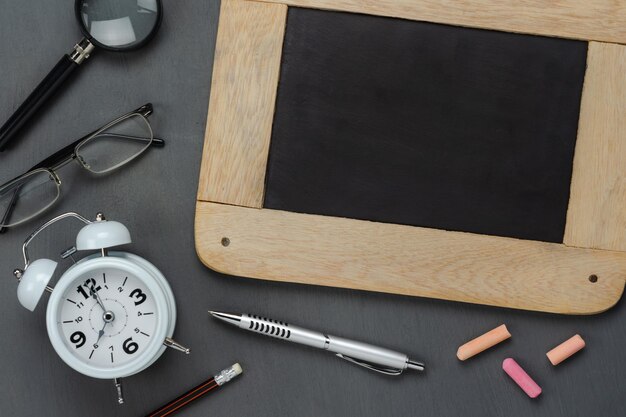 Photo high angle view of slate with chalks alarm clock on table