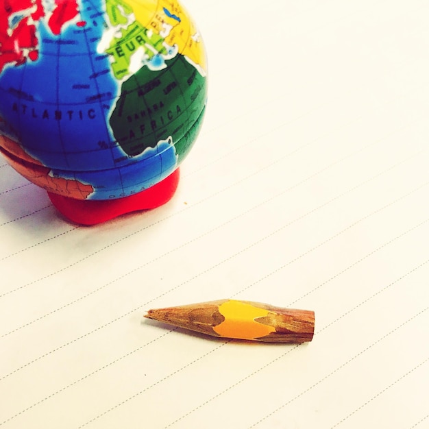High angle view of small pencil and globe over paper