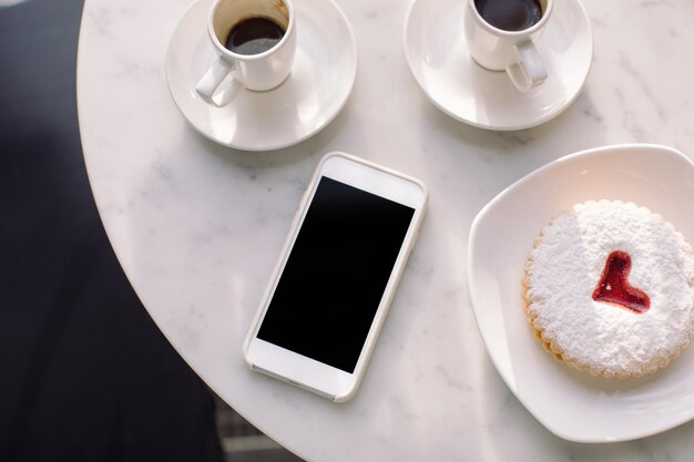 High angle view of smart phone by breakfast on table