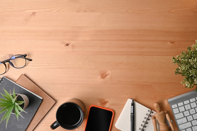 High angle view of smart phone, notebook, glasses and coffee cup on wooden desk.