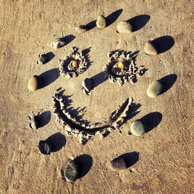 Photo high angle view of smiley face drawn on sand at beach