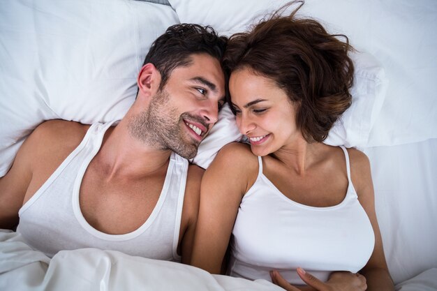 High angle view of smiling couple relaxing on bed