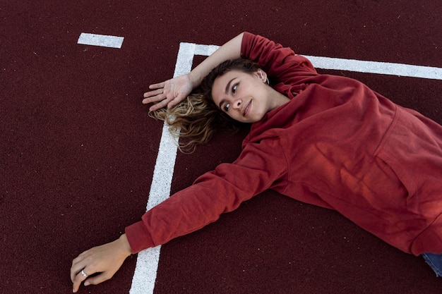 Foto vista ad alto angolo di una giovane donna sorridente sdraiata sulla pista sportiva