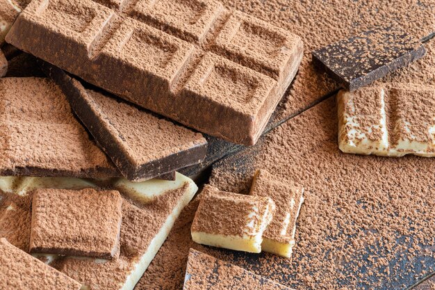 Photo high angle view of some chicolate bars covered with some cocoa powder over a wooden table