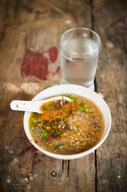 Photo high angle view of soup in bowl and drinking glass on wooden table