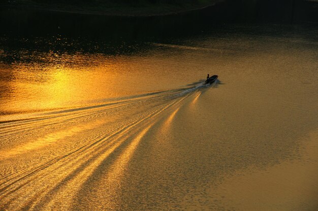 Photo high angle view of speedboat moving in river during sunset