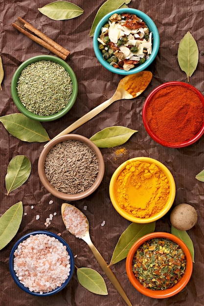 High angle view of spices in colorful bowls on paper
