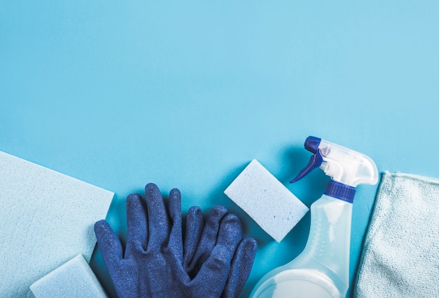 High angle view of spray bottle, gloves and sponge on blue background