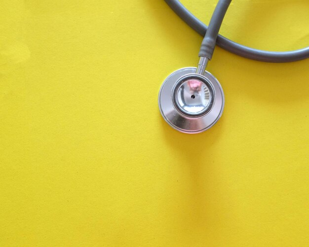 High angle view of stethoscope on yellow background