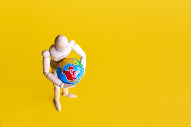 Photo high angle view of stuffed toy yellow background wooden mannequin with globe  earth concept