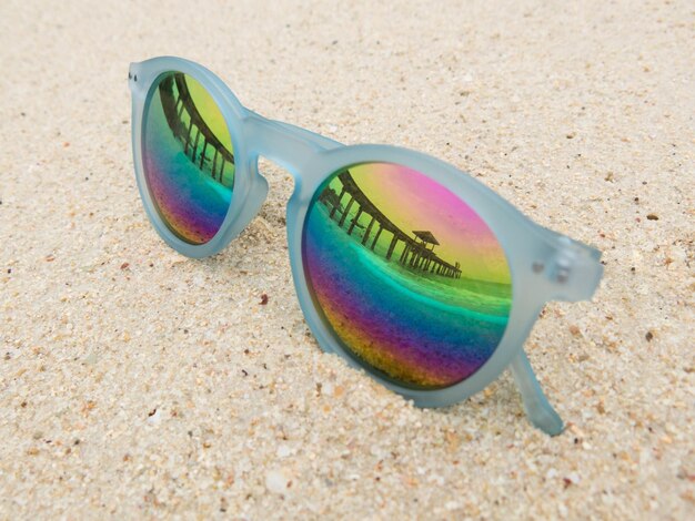 Photo high angle view of sunglasses on sand with reflection