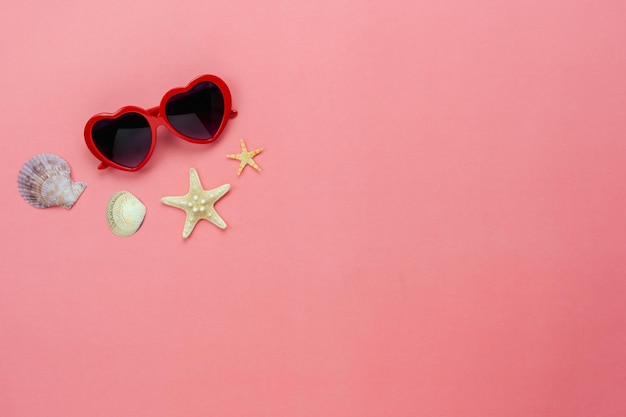 High angle view of sunglasses and seashells on pink background