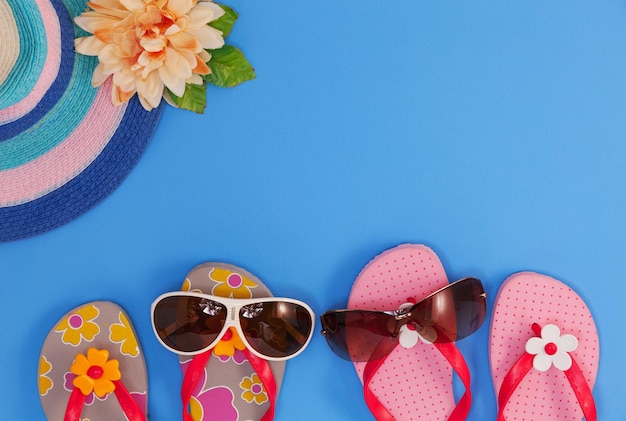 Photo high angle view of sunglasses with flip-flops on blue background