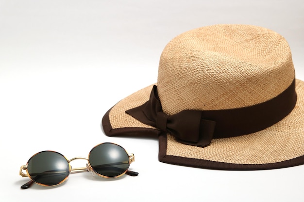 Foto vista ad alto angolo di occhiali da sole con cappello su sfondo bianco